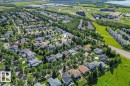 Aerial perspective showcasing a residential area with mature trees, green spaces, and a lake in the distance - 16 Harrold Place, St. Albert, AB  - Outdoor With View 