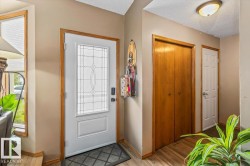 Entryway featuring a white door with decorative glass inserts, wood-finish flooring, a wood-finish bi-fold closet, and a white panel door - 