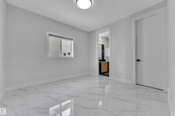 Spacious interior featuring large format marble-look tile flooring, light gray walls, a modern ceiling light fixture, and white trim - 