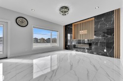 Spacious room featuring white and grey marbled tile flooring, a large picture window, and a contemporary fireplace with a black marble surround and wood slat detailing - 