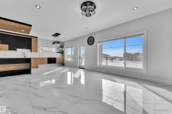 Spacious room featuring large format marble-look tile flooring, contemporary recessed lighting, and a modern kitchen with two-tone cabinetry and geometric backsplash - 