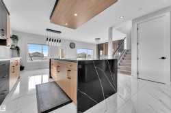 Kitchen island featuring a black countertop with white veining and light wood-finish cabinetry - 