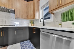 Contemporary kitchen featuring two-tone cabinetry with light wood-finish upper cabinets and dark lower cabinets, complemented by gold-tone hardware - 