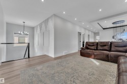 Open-concept living space with recessed lighting, light wood-finish flooring, and a modern chandelier - 
