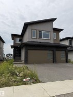 Contemporary two-story residence with a multi-tone exterior, featuring a prominent two-car garage with modern sectional doors - 