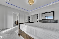 Recessed lighting and a decorative chandelier illuminate this room, featuring a tray ceiling with accent lighting - 