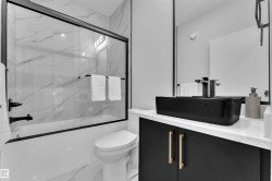 Modern bathroom featuring a matte black vessel sink, black vanity with gold-tone hardware, and a white countertop - 