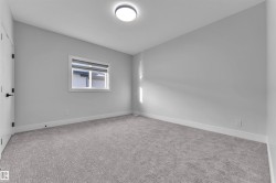 Well-lit room featuring light gray walls, textured gray carpeting, white trim, and a window with integrated blinds - 