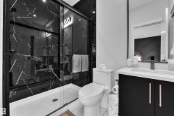 Modern bathroom featuring a glass-enclosed shower with black marble-patterned wall tiles, a white shower pan, a black vanity cabinet with gold-toned hardware, a white countertop, and a rectangular sink with a matte black faucet - 