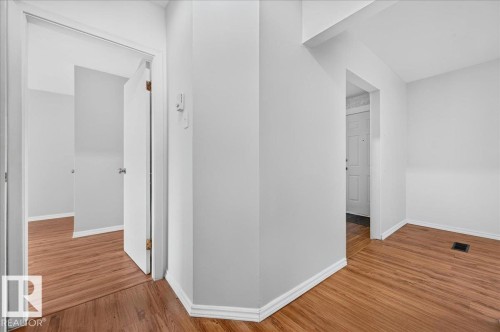 Interior hallway with wood-finish flooring, crisp white baseboards, and light gray wall paint - 12134 42 Street Nw, Edmonton, AB - Indoor Photo Showing Other Room