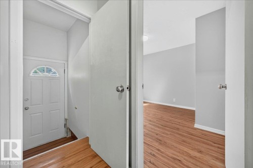 Entryway with wood-finish flooring, white paneled door with arched glass insert, and neutral wall tones - 12134 42 Street Nw, Edmonton, AB - Indoor Photo Showing Other Room
