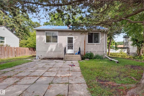 Exterior facade featuring light-colored stucco, a blue roof, and multiple window openings - 12134 42 Street Nw, Edmonton, AB - Outdoor