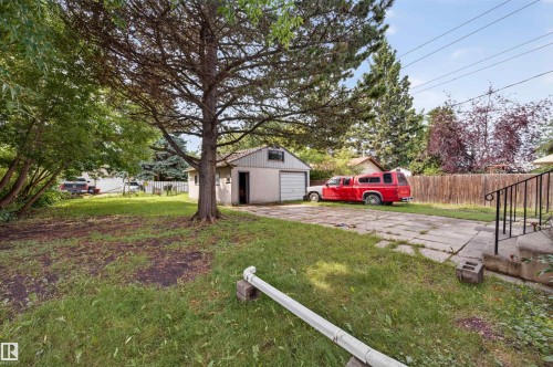 Spacious backyard featuring a detached garage with a single bay, concrete driveway, and mature landscaping - 12134 42 Street Nw, Edmonton, AB - Outdoor