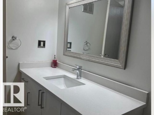 Modern vanity featuring an integrated rectangular sink, sleek chrome faucet, and bright white countertop - #103 10023 164St St Nw, Edmonton, AB - Indoor Photo Showing Bathroom