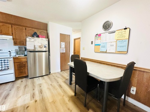 Kitchen area featuring wood-finish flooring, wood cabinetry, and a stainless steel refrigerator - 221 Parkview Drive, Wetaskiwin, AB - Indoor Photo Showing Other Room