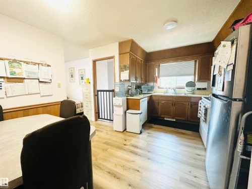 Kitchen featuring wood-finish flooring, wood cabinetry, stainless steel refrigerator, and a window above the sink - 221 Parkview Drive, Wetaskiwin, AB - Indoor