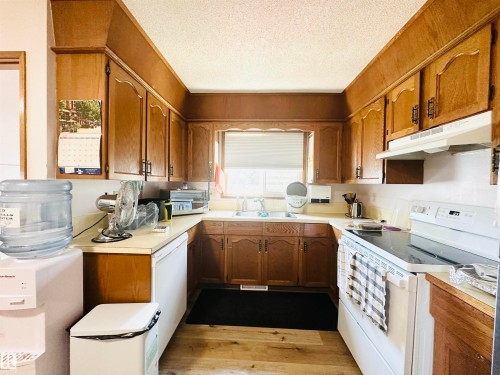 U-shaped kitchen featuring wood-finish cabinetry, white countertops, and wood-finish flooring - 221 Parkview Drive, Wetaskiwin, AB - Indoor Photo Showing Kitchen With Double Sink