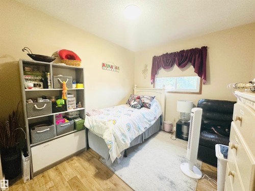 Bedroom featuring wood-finish flooring, a single window with wood trim, and neutral-toned walls - 221 Parkview Drive, Wetaskiwin, AB - Indoor Photo Showing Bedroom