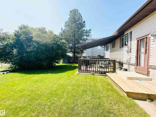Expansive backyard featuring a manicured lawn, established landscaping, and a wooden deck - 221 Parkview Drive, Wetaskiwin, AB - Outdoor With Deck Patio Veranda