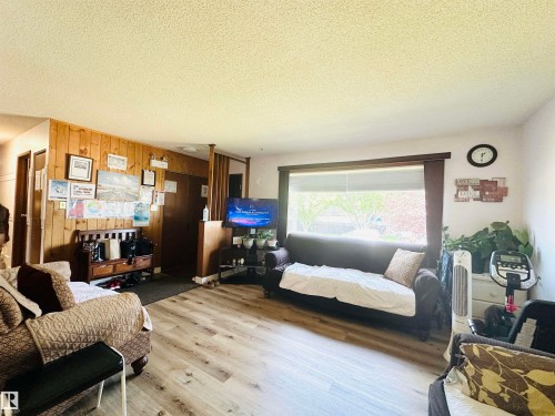 Spacious interior room featuring light wood-finish flooring, a large window with blinds, and white wall finishes - 221 Parkview Drive, Wetaskiwin, AB - Indoor