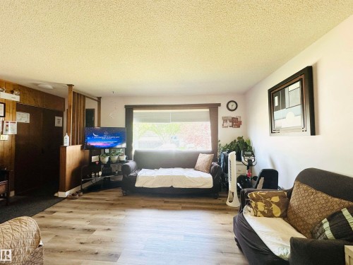 Bright living area featuring wood-finish flooring, a large window with horizontal blinds, and smooth white walls - 221 Parkview Drive, Wetaskiwin, AB - Indoor