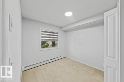 Carpeted room featuring a single window with blinds, baseboard heating, and light-colored walls - 