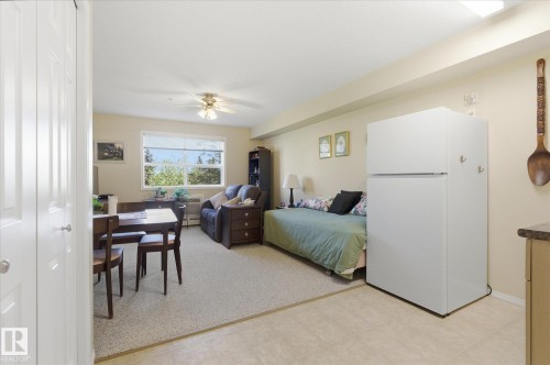 Open-concept living area featuring a large window, a ceiling fan, and carpet flooring - #230 8802 Southfort Dr, Fort Saskatchewan, AB - Indoor