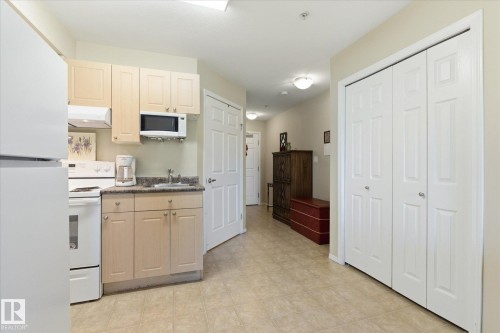 Efficient kitchen area featuring light wood-finish cabinetry, a white refrigerator, a white stove, and a built-in microwave - #230 8802 Southfort Dr, Fort Saskatchewan, AB - Indoor Photo Showing Kitchen