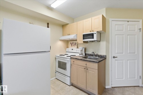 Kitchenette featuring a white refrigerator, electric range, and over-the-range microwave - #230 8802 Southfort Dr, Fort Saskatchewan, AB - Indoor Photo Showing Kitchen