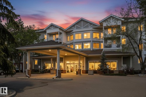 Multi-story building featuring a covered entrance with stone-clad columns and an expansive driveway - #230 8802 Southfort Dr, Fort Saskatchewan, AB - Outdoor