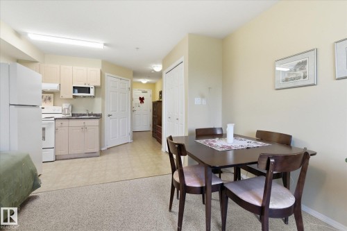 Compact kitchen area featuring neutral cabinetry and white appliances, including a refrigerator, stove, and built-in microwave - #230 8802 Southfort Dr, Fort Saskatchewan, AB - Indoor