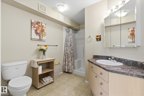 Bathroom featuring a corner vanity with a built-in sink, a wall-mounted medicine cabinet with integrated lighting, and a shower stall - #230 8802 Southfort Dr, Fort Saskatchewan, AB - Indoor Photo Showing Bathroom