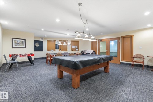 Spacious recreation room featuring patterned carpet flooring, recessed lighting, and a multi-light fixture - #230 8802 Southfort Dr, Fort Saskatchewan, AB - Indoor Photo Showing Other Room