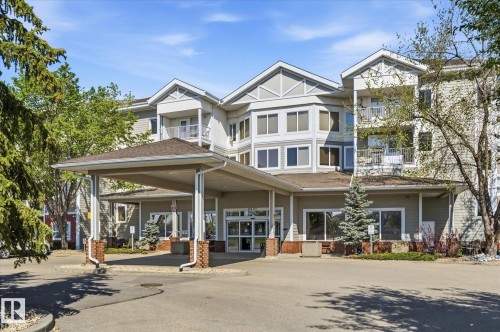 Multistory building with light-colored siding and a prominent porte-cochère entry - #230 8802 Southfort Dr, Fort Saskatchewan, AB - Outdoor With Facade