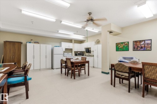 Spacious common area featuring a full kitchen with white cabinetry and appliances - #230 8802 Southfort Dr, Fort Saskatchewan, AB - Indoor