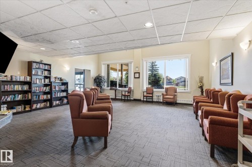 Spacious common area featuring patterned carpet flooring, recessed ceiling lighting, and large windows - #230 8802 Southfort Dr, Fort Saskatchewan, AB - Indoor