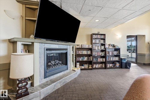 Fireplace feature wall with a tile surround and hearth - #230 8802 Southfort Dr, Fort Saskatchewan, AB - Indoor With Fireplace