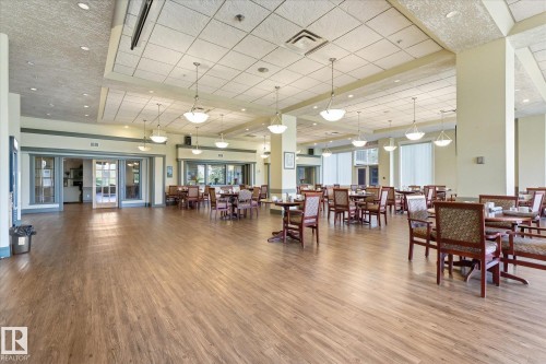 Spacious dining area featuring wood-finish flooring, recessed lighting, and suspended bowl light fixtures - #230 8802 Southfort Dr, Fort Saskatchewan, AB - Indoor