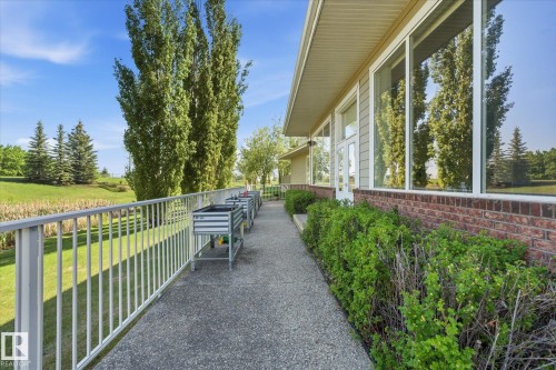 Exterior walkway with a metal railing and a concrete surface - #230 8802 Southfort Dr, Fort Saskatchewan, AB - Outdoor