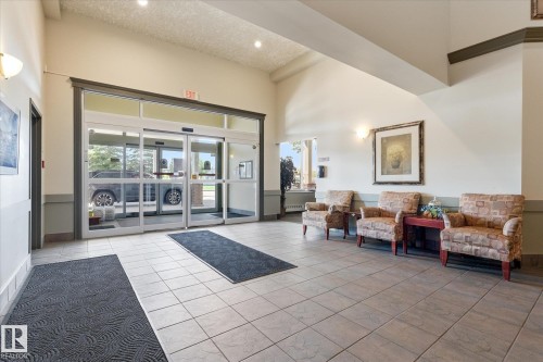 Spacious entry foyer featuring automatic glass doors, large format tile flooring, and a vaulted ceiling - #230 8802 Southfort Dr, Fort Saskatchewan, AB - Indoor