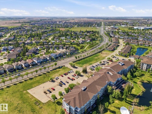 Aerial perspective showcasing a residential community with single-family homes and multi-story apartment buildings - #230 8802 Southfort Dr, Fort Saskatchewan, AB - Outdoor With View