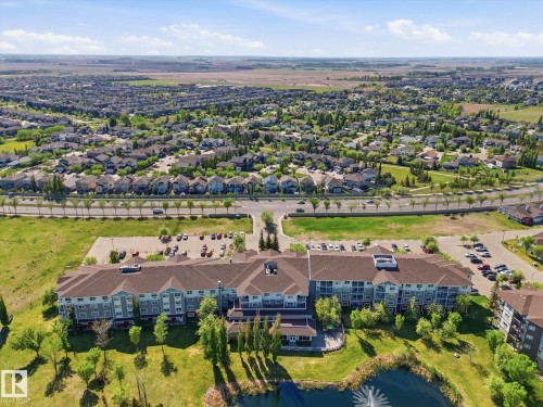 Multi-story residential complex featuring private balconies, ample surface parking, and extensive green spaces - #230 8802 Southfort Dr, Fort Saskatchewan, AB - Outdoor With View