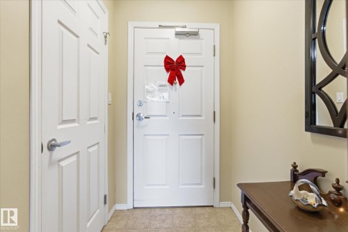 Entryway with two white paneled doors, neutral wall paint, and tiled flooring - #230 8802 Southfort Dr, Fort Saskatchewan, AB - Indoor Photo Showing Other Room