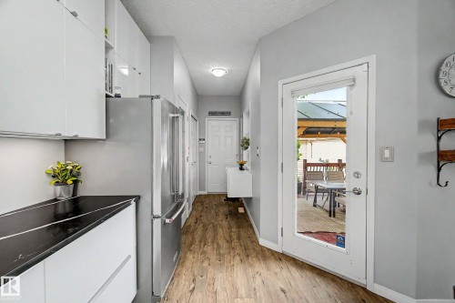 Hallway featuring wood-finish flooring, light gray wall paint, and a glass-paneled exterior door - 9130 100A Avenue Nw, Edmonton, AB - Indoor Photo Showing Other Room