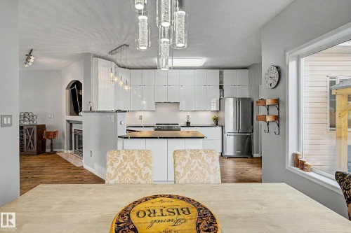 Modern kitchen featuring white cabinetry, stainless steel appliances, a center island with black countertop, and contemporary lighting fixtures - 9130 100A Avenue Nw, Edmonton, AB - Indoor Photo Showing Other Room