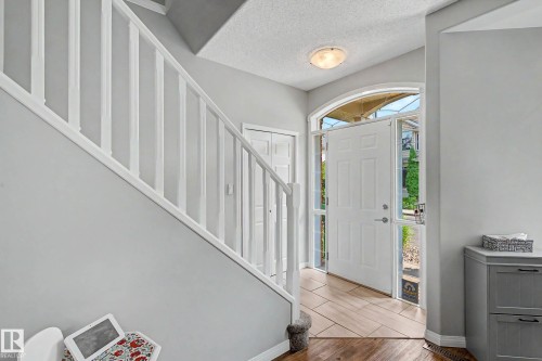 Inviting entryway featuring a white paneled door with an arched transom, sidelight windows, and a combination of wood-finish and tiled flooring - 9130 100A Avenue Nw, Edmonton, AB - Indoor Photo Showing Other Room