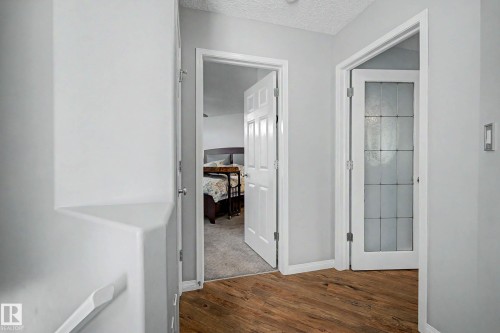 Hallway with wood-finish flooring, light grey wall paint, and white trim - 9130 100A Avenue Nw, Edmonton, AB - Indoor Photo Showing Other Room