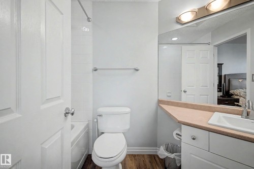 Full bathroom featuring a single vanity with an integrated sink, a large wall-mounted mirror, a toilet, and a shower-over-tub combination with white subway tile surround - 9130 100A Avenue Nw, Edmonton, AB - Indoor Photo Showing Bathroom