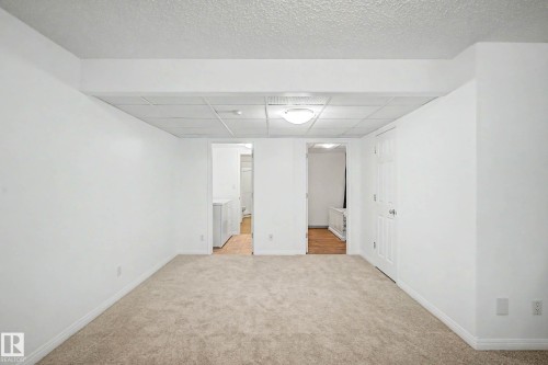 Spacious room featuring neutral carpeting, white walls, and a drop ceiling with integrated lighting - 9130 100A Avenue Nw, Edmonton, AB - Indoor Photo Showing Other Room