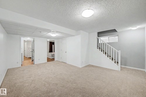 Carpeted room with a full staircase featuring white railings and a single window - 9130 100A Avenue Nw, Edmonton, AB - Indoor Photo Showing Other Room